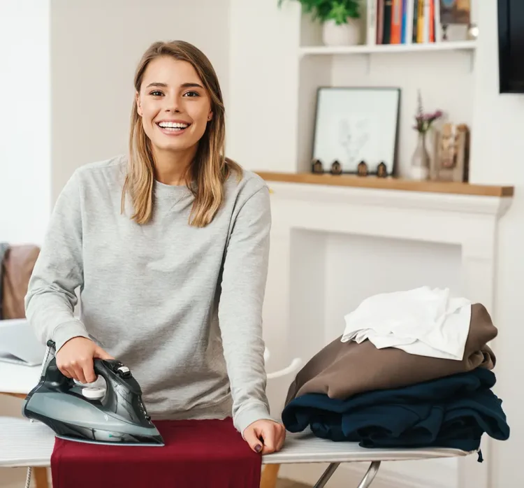 Lächelnde Frau steht am Bügelbrett
