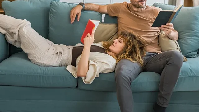 Mann und Frau gemeinsam lesend auf einer Couch - Services Header (mobil)